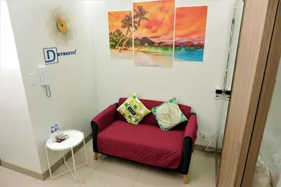 a living room with a red couch and two paintings at Shore Residences MOA Dynastel Staycation in Manila