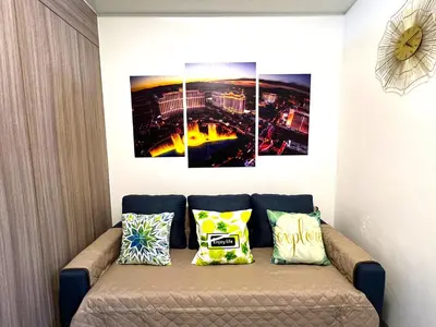 a couch in a room with three paintings on the wall at Shore Residences MOA Dynastel Staycation in Manila