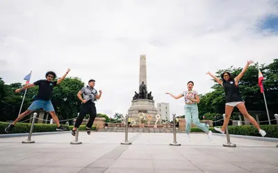 a group of people jumping over poles in front of a monument at Mad Monkey Manila in Manila