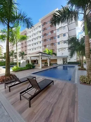 a hotel with a swimming pool and palm trees at Sojourn at SMDC Hope Residences in Trece Martires