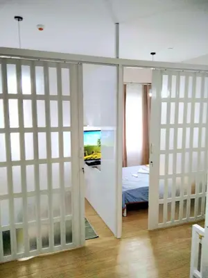 a room with sliding doors and a bedroom with a bed at Sojourn at SMDC Hope Residences in Trece Martires
