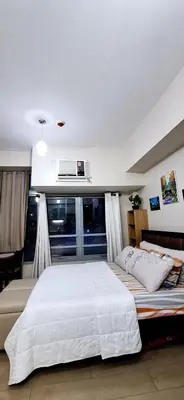 a bedroom with a large white bed and a window at Eastwood LeGrand 3 Cozy & Modern Studio Type Condominium in Manila
