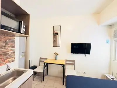 a small kitchen with a table and a tv on the wall at Hassle Free Check In and Out With Unli WiFi Netflix in Manila