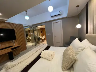 a bedroom with a large white bed and a television at Hotel Vibe Condo at Uptown Parksuites BGC in Manila