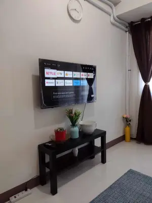a tv on a wall with a table in a room at G&M Comfy place for your stay at SMDC Coast Residences in Manila
