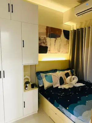 a small bedroom with a bed with white cabinets at Stylist Luxe Condo near Mall of Asia - Shore 3 in Manila