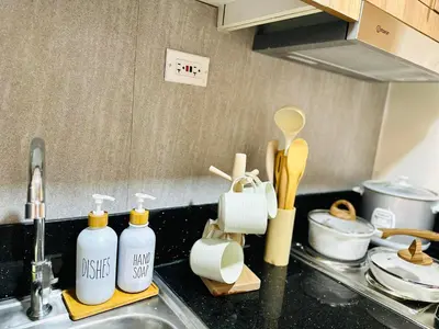 a kitchen counter with detergent bottles and a sink at Stylist Luxe Condo near Mall of Asia - Shore 3 in Manila