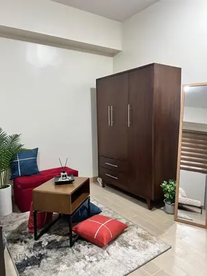 a living room with a red couch and a wooden cabinet at Brand New Studio w/ Washer in Manhattan Plaza Tower ll in Manila