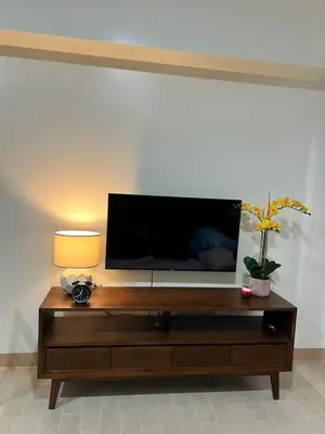 a flat screen tv sitting on top of a wooden entertainment center at Brand New Studio w/ Washer in Manhattan Plaza Tower ll in Manila
