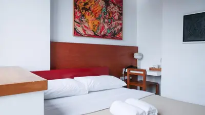 a bedroom with a bed and a table and a painting at Cayco House by Hotel Durban in Manila