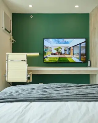 a bedroom with a flat screen tv on a green wall at BGC Suite with Golf Course View in Manila