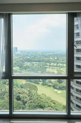 a window in a building looking out at a golf course at BGC Suite with Golf Course View in Manila