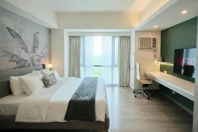 a hotel room with a bed and a desk and a computer at BGC Suite with Golf Course View in Manila