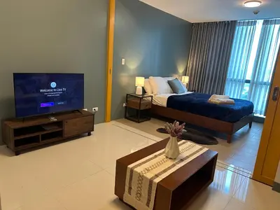 a bedroom with a bed and a tv and a table at Deluxe Suite in One Uptown, BGC with Mall Fountain View in Manila