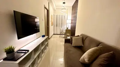 a living room with a couch and a flat screen tv at Premier Luxury Suite near SM Mall of Asia Arena & DFA with Free Parking in Manila