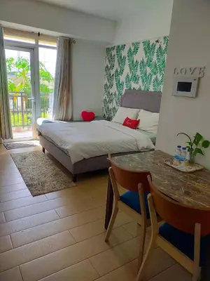 a bedroom with a bed and a table and a tableablish at Rose condotel Newport in Manila