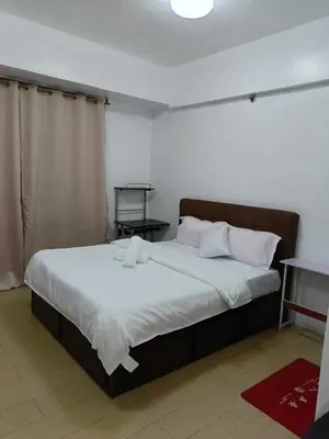 a bedroom with a large bed with white sheets and pillows at Rose condotel Newport in Manila