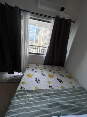 a bed in a room with a window with a bedspread with flowers at Connie's Fame Residence City Haven in Manila