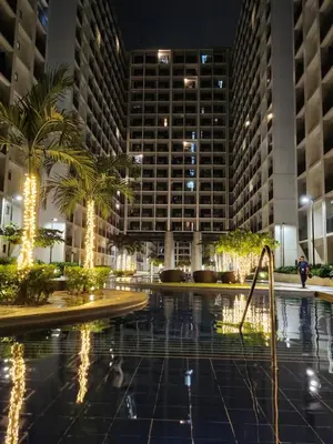 a pool at night with palm trees and buildings at Goshen E320 in Manila