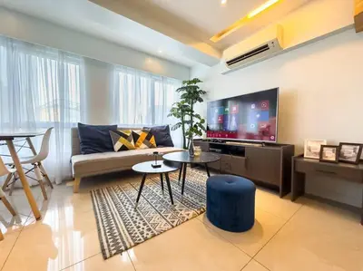 a living room with a couch and a flat screen tv at A2J Luxury 2BR BGC Suite Near High Street, Malls in Manila