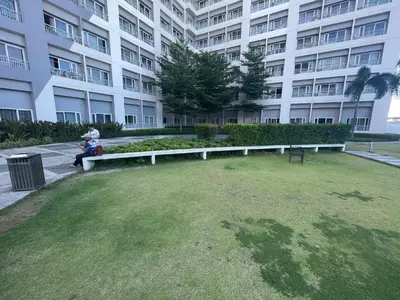 a person sitting on a bench in front of a building at Grace Residences Pool View Free Wi-Fi near BGC and McKinley 2050 in Manila