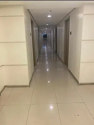 an empty hallway of a building with white floors and doors at Grace Residences Pool View Free Wi-Fi near BGC and McKinley 2050 in Manila