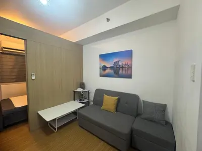 a living room with a couch and a bed at Grace Residences Condotel Paris & Singapore Concept Near McKinley in Manila