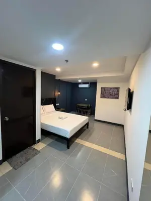 a bedroom with a white bed and a table at Maine City Residences Tramo in Manila