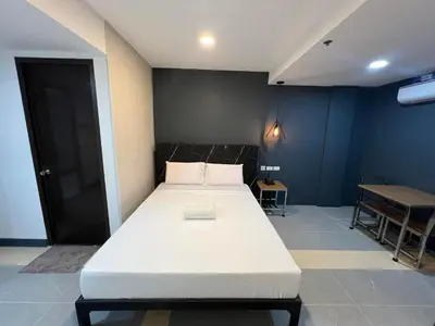 a large white bed in a room with a table at Maine City Residences Tramo in Manila