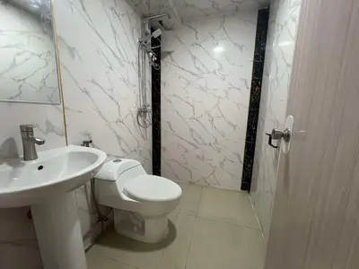 a white bathroom with a toilet and a sink at Maine City Residences Tramo in Manila