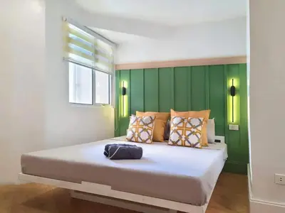 a bedroom with a large bed with a green wall at BGC - Two Bedroom Condo with Game Room high speed WiFi in Manila