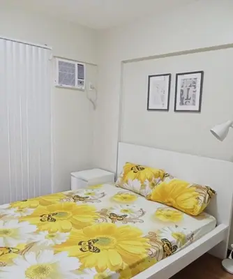 a bedroom with a bed with yellow flowers on it at Asteria Residences Annabel CozyPlace highspeed wifi in Manila