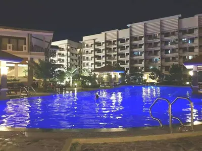 a large swimming pool in front of a hotel at night at Asteria Residences Annabel CozyPlace highspeed wifi in Manila