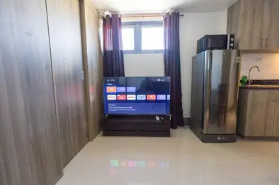 a room with a large television and a refrigerator at Bohemian 1-BR Condo in Mandaluyong in Manila