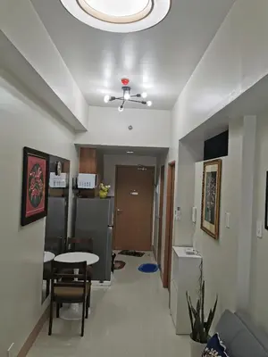 a living room with a table and a kitchen at Shore 3 residence in Manila