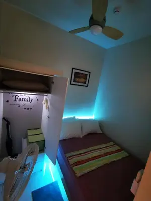 a room with a bed with a ceiling fan and lights at Good Day staycation shore 3 in Manila