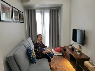 a woman sitting on a couch in a living room at Good Day staycation shore 3 in Manila