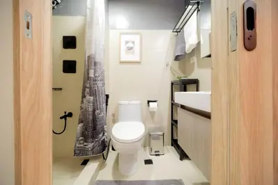 a bathroom with a toilet and a sink with a picture of a building at Shore 3 Mall of Asia - Sofian Suites in Manila