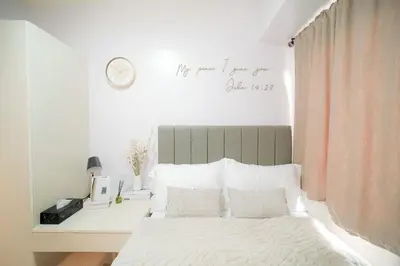 a bedroom with a bed and a desk with a clock on the wall at Shore 3 Mall of Asia - Sofian Suites in Manila