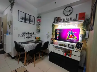 a dining room with a table and a tv on a wall at Smdc Breeze Residence in Manila