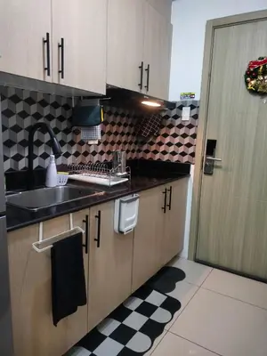a kitchen with wooden cabinets and a sink and a checkered floor at Smdc Breeze Residence in Manila