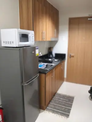 a kitchen with a microwave on top of a refrigerator at Cozy Condo near Mall of Asia in Manila
