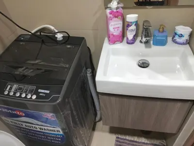 a microwave sitting next to a sink next to a counter at Cozy Condo near Mall of Asia in Manila