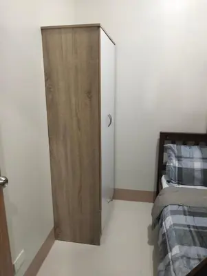 a bedroom with a wooden cabinet next to a bed at Cozy Condo near Mall of Asia in Manila