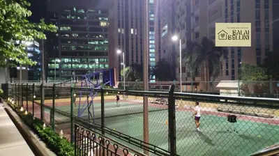 a group of people playing tennis on a tennis court at Condo in McKinley Hill near Grand Canal Mall (Balai Bellini) in Manila