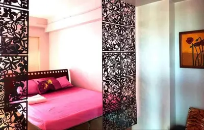 a bedroom with a pink bed and a black and white wall at Backpackers Transient Room in Manila