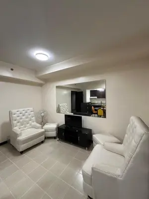 a living room with white furniture and a mirror at The Ivory San Lorenzo Place Makati in Manila