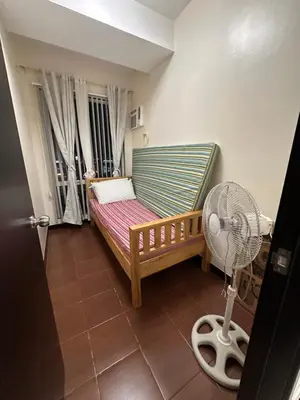 a room with a bed and a fan in a room at The Ivory San Lorenzo Place Makati in Manila