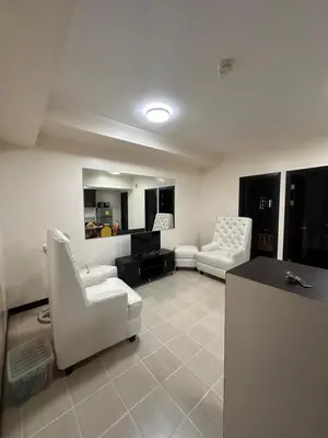 a living room with two white chairs and a table at The Ivory San Lorenzo Place Makati in Manila