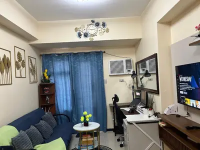 a living room with a blue couch and a desk at Bayfront Suite in Pasay Near NAIA Terminal, PICC, Star City, MOA and US Embassy - Pet-Friendly, Wi-Fi & Netflix, Free Swimming Pool, Sauna and Gym, Work from Home Ready in Manila
